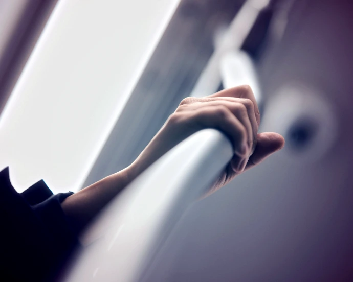 Hand holding onto a white railing indoors.